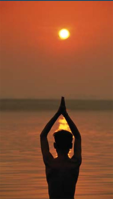 The sun rising over the Bay of Bengal with the silhouette of a man in a yoga pose.