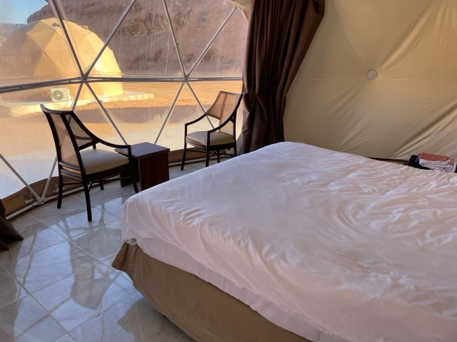 inside a luxury camp room, showing the bed and view out of the window