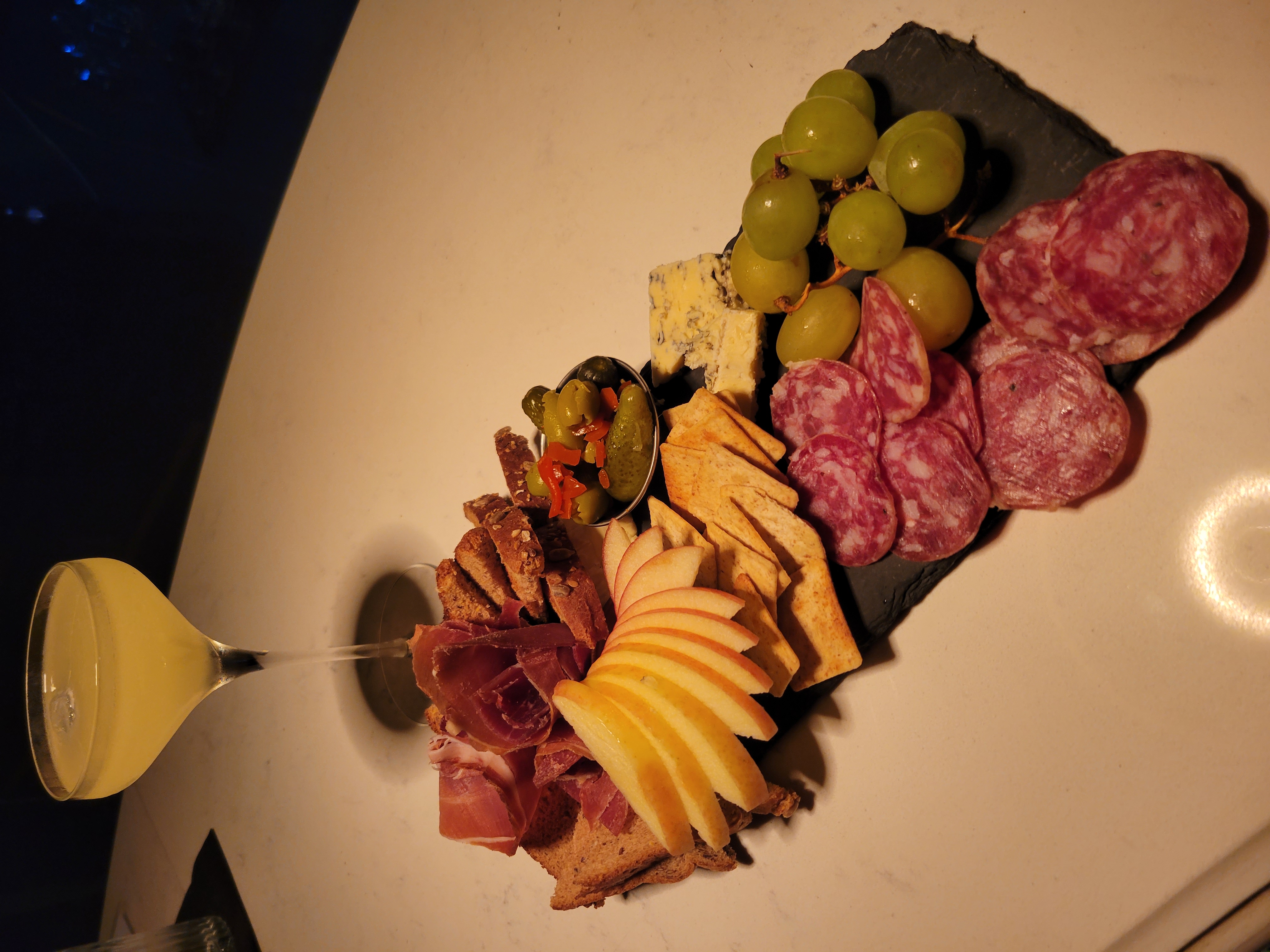 A plate of cheese and meats and a cocktail