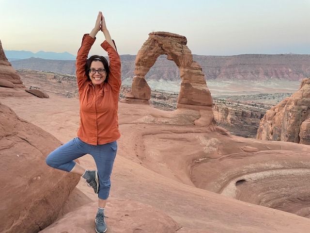lady in yoga pose at Delicate Arch - Arches National Park, Utah