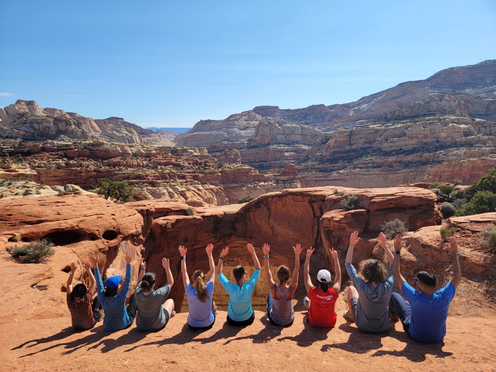 A group of trekkers holding their arms in the air at Cassidy Arch Trail Utah