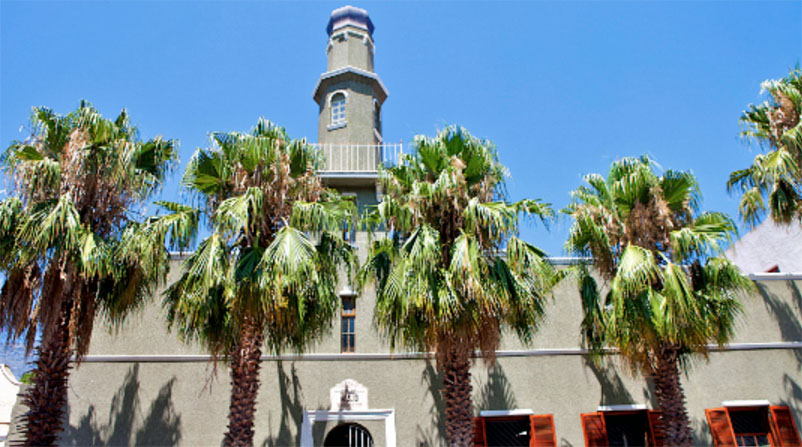 Green palm trees in front of a mosque with blue sky in the background