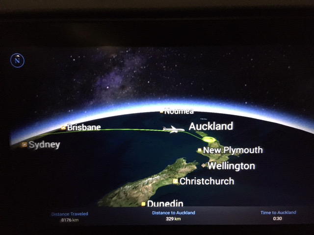 A seat-back screen image showing a flight approaching Auckland, New Zealand.