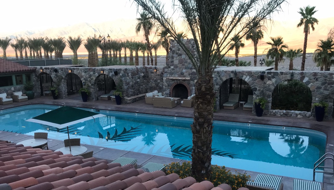 An outdoor swimming pool with palm trees behind, in Death Valley, California