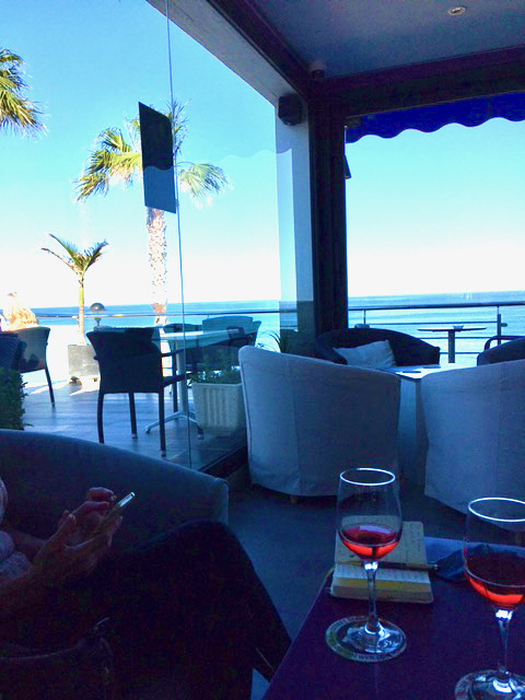 Looking out on the sea from a bar, with 2 glasses of wine on a table in the foreground