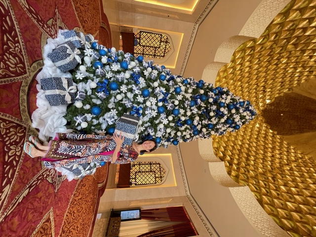 lady standing by a blue and white decorated christmas tree