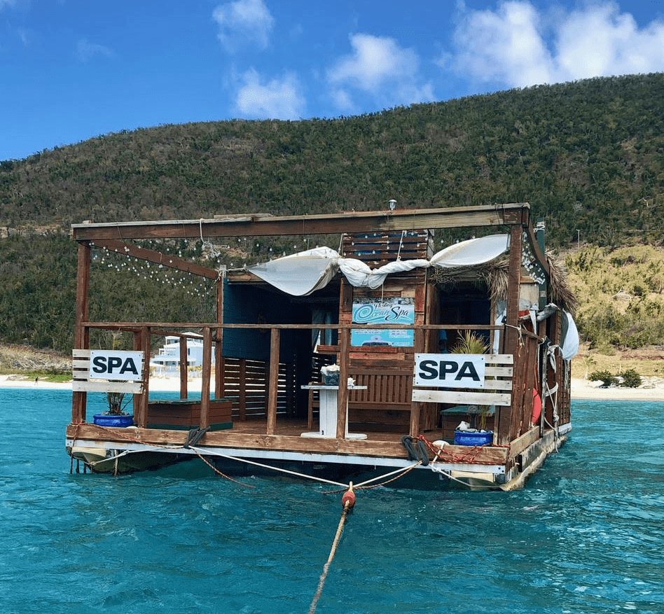 A wooden spa boat floating on blue water in the Caribbean.