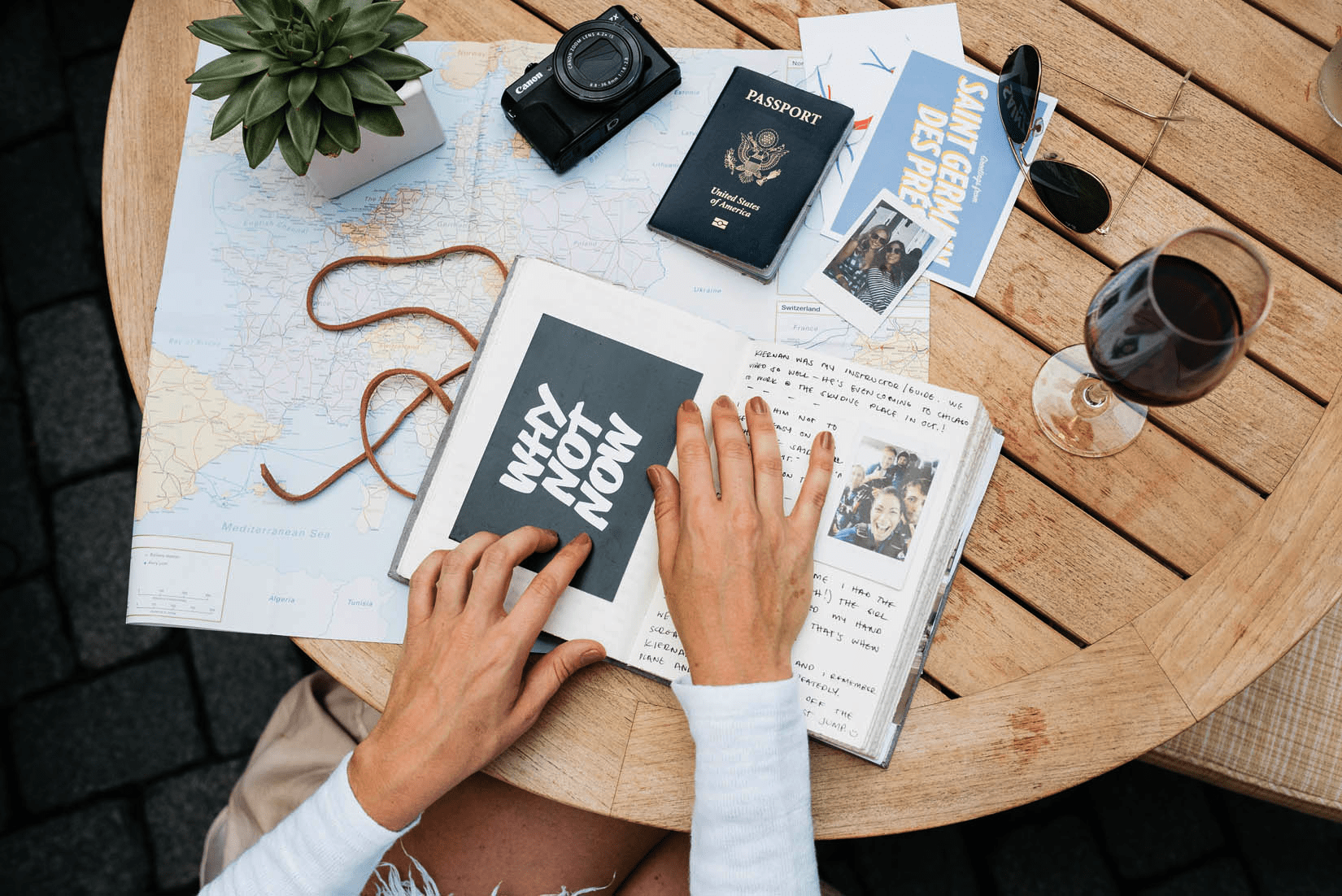 A table full of items you need to plan a trip, including passports, camera, a map and a travel log book